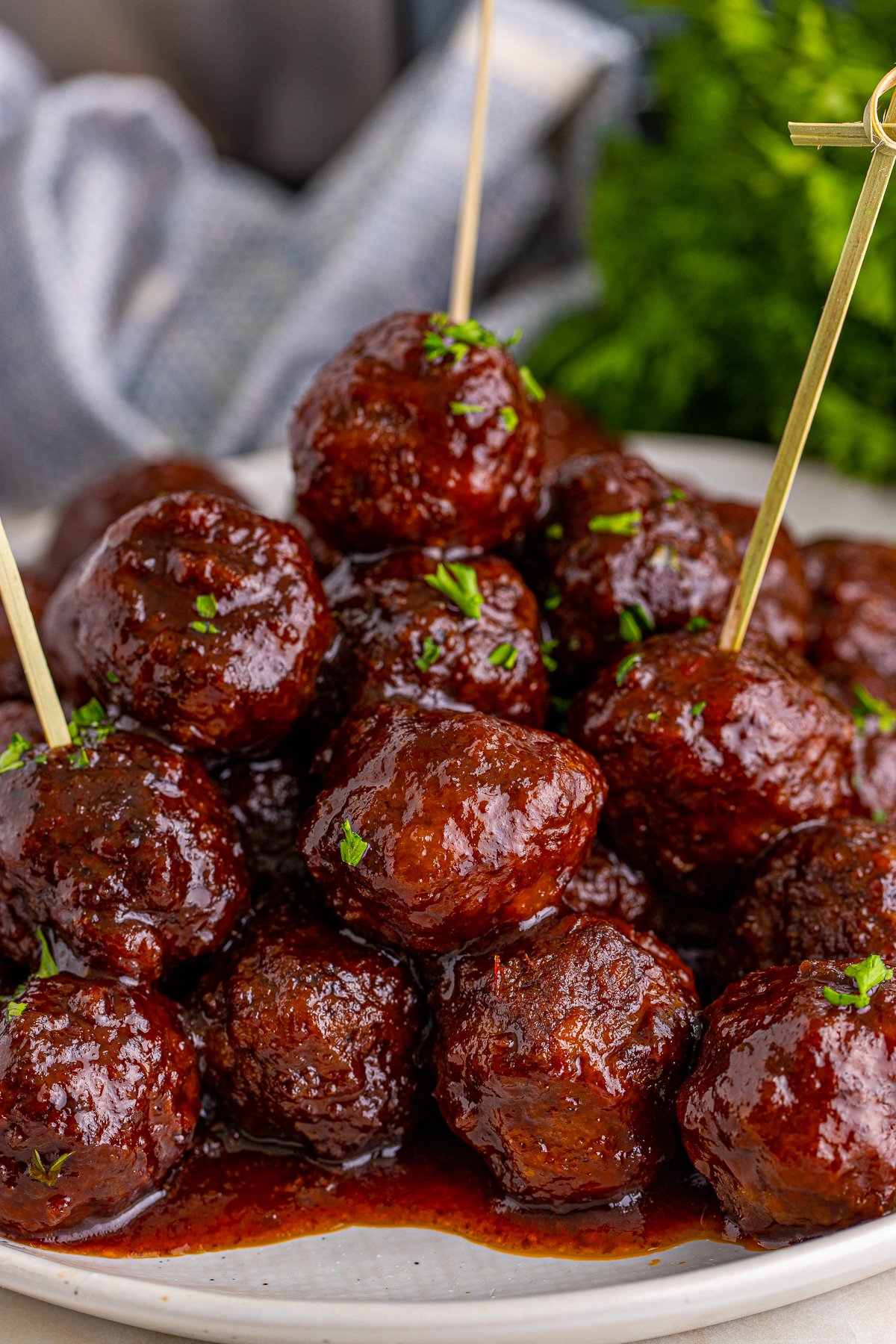 Stacked Crock Pot Grape Jelly Meatballs on plate with toothpicks.