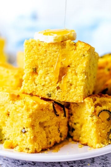 Square image of Jalapeno Cornbread with butter and honey drizzle.