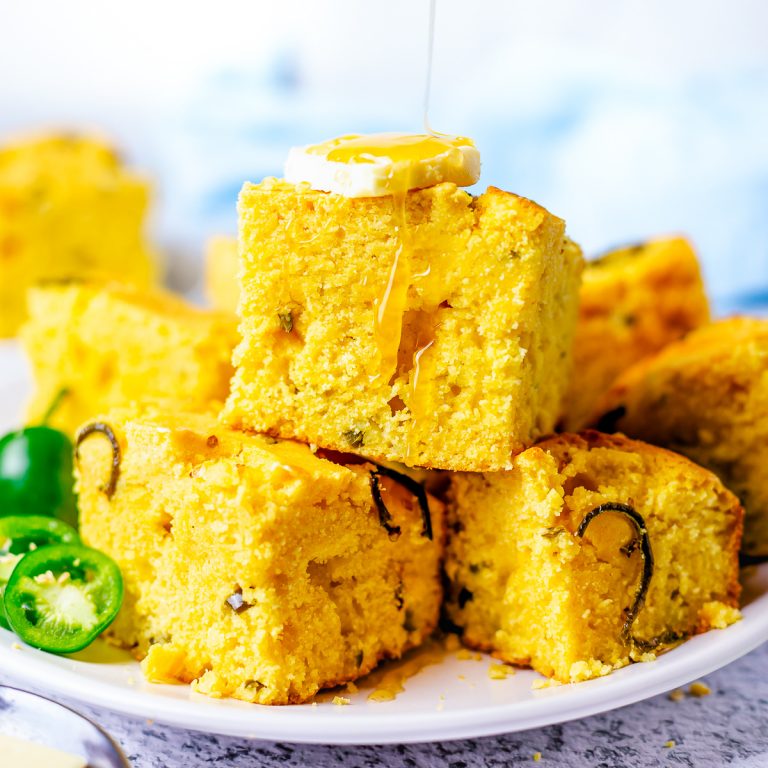 Square image of Jalapeno Cornbread with butter and honey drizzle.