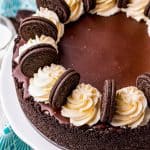 A whole no bake Oreo cheesecake topped with chocolate ganache, whipped cream swirls, and Oreos.