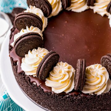 A whole no bake Oreo cheesecake topped with chocolate ganache, whipped cream swirls, and Oreos.