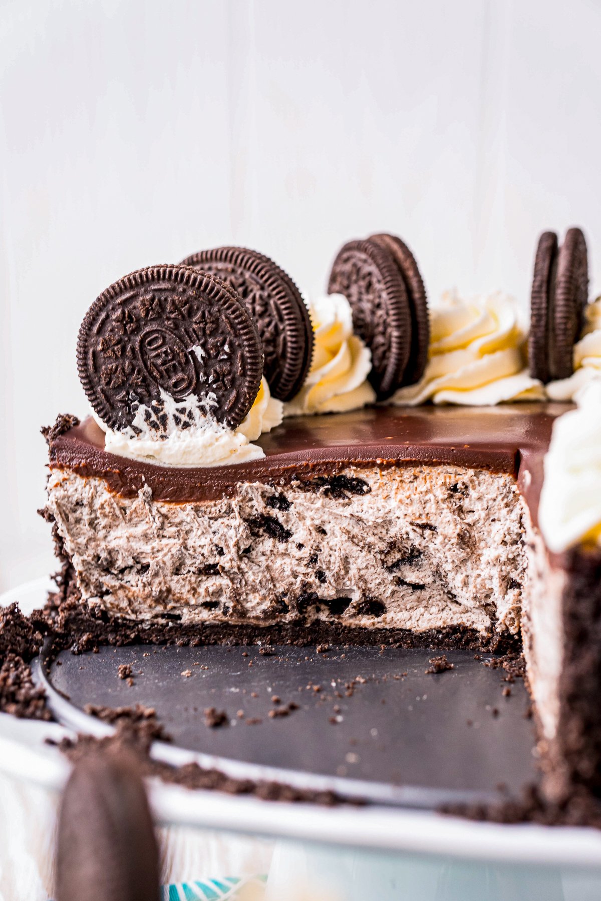 No Bake Oreo Cheesecake on stand with slices taken out showing inside.