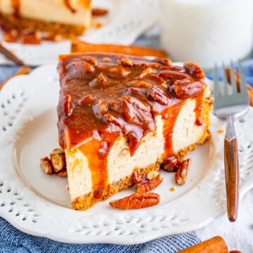 Square image of cheesecake on plate with topping dripping down sides.