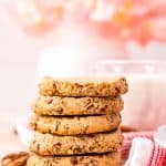 Five stacked cookies on top of one another with milk in background.