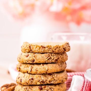 Five stacked cookies on top of one another with milk in background.