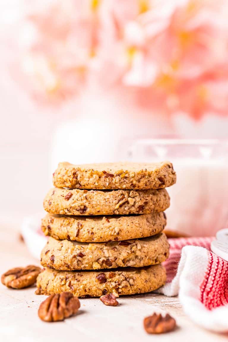 Five stacked cookies on top of one another with milk in background.