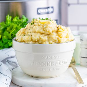 Square image of white serving bowl of Slow Cooker Mashed Potatoes.