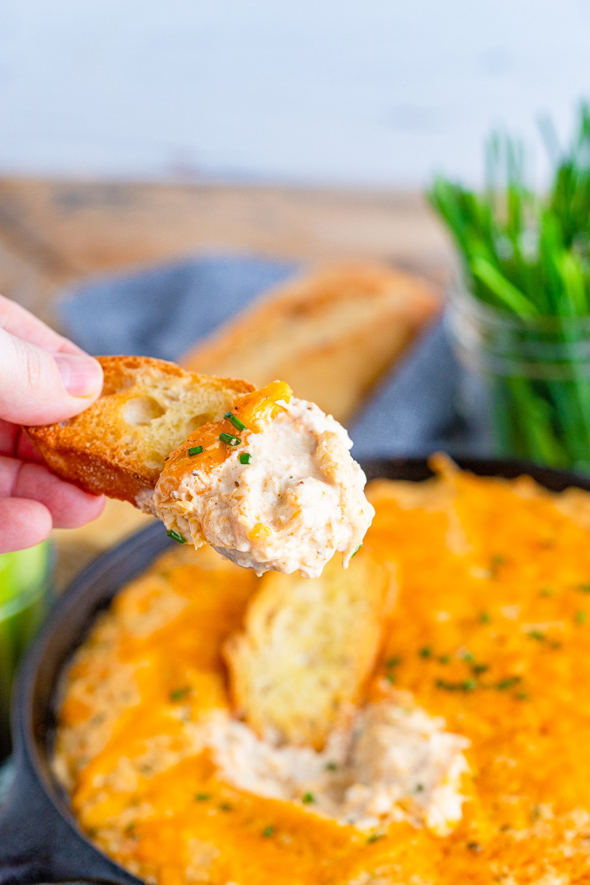 Hand holding up a piece of bread with some Smoked Crab Dip Recipe on it.