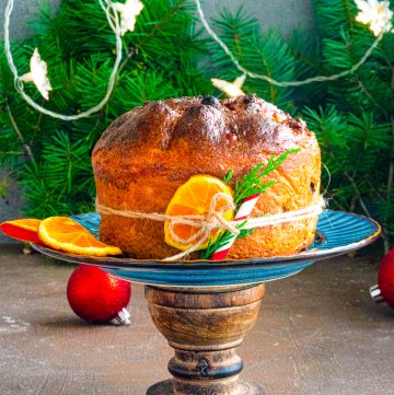 Panettone Recipe on serving stand with oranges and a tie around it.
