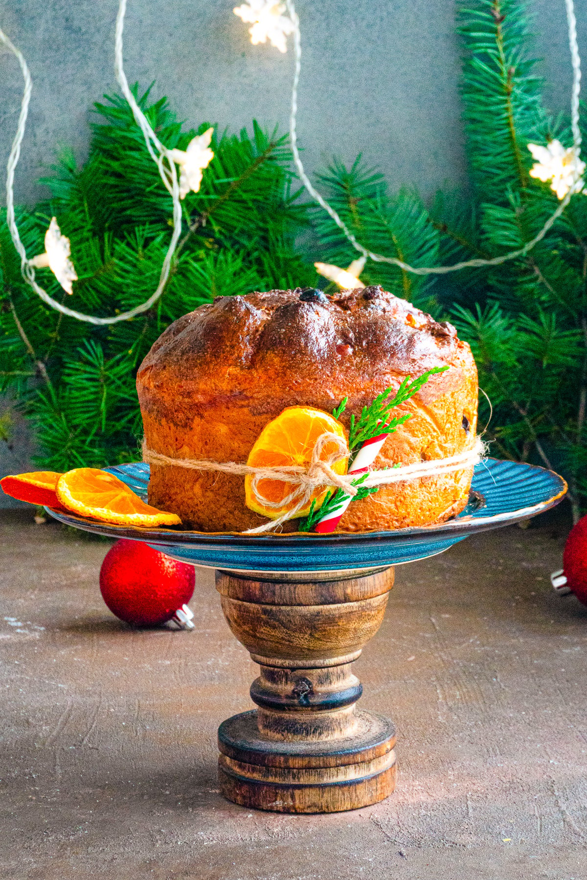 Panettone Recipe on serving stand with oranges and a tie around it.