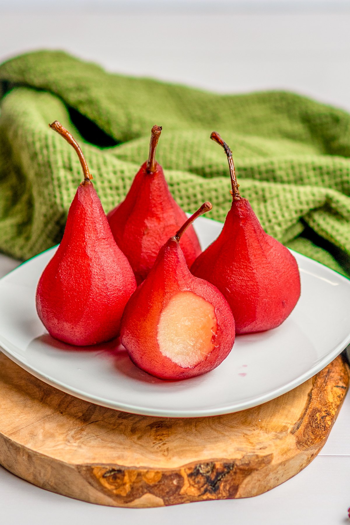 Four Poached Pears on white plate with bite taken out of one.