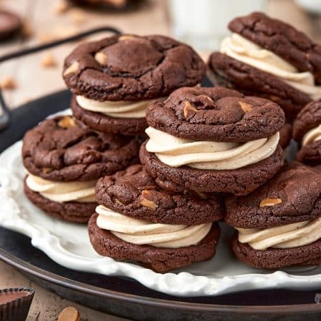 Stacked Reese's Sandwich Cookies on parchment lined round tray.