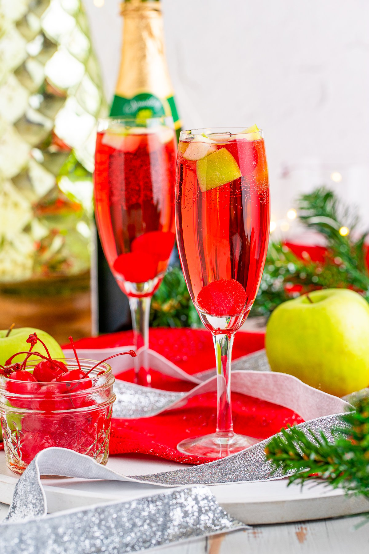 Two stemmed glasses of Christmas Mimosa Mocktails with garnishes.