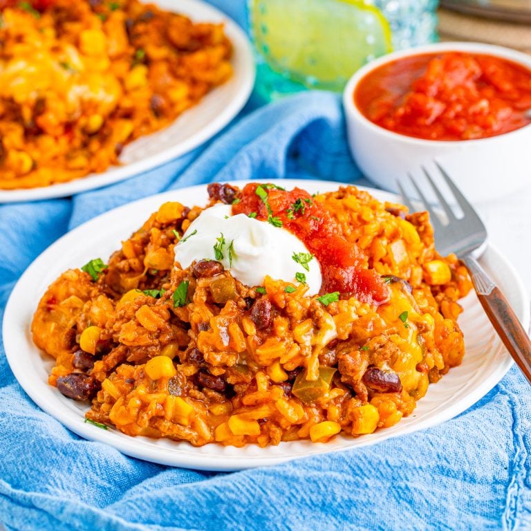 Square image of casserole on white plate with sour cream and salsa.
