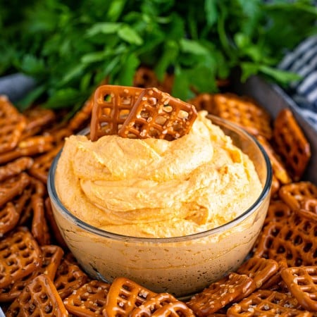 Square image of dip in bowl with pretzels in dip.