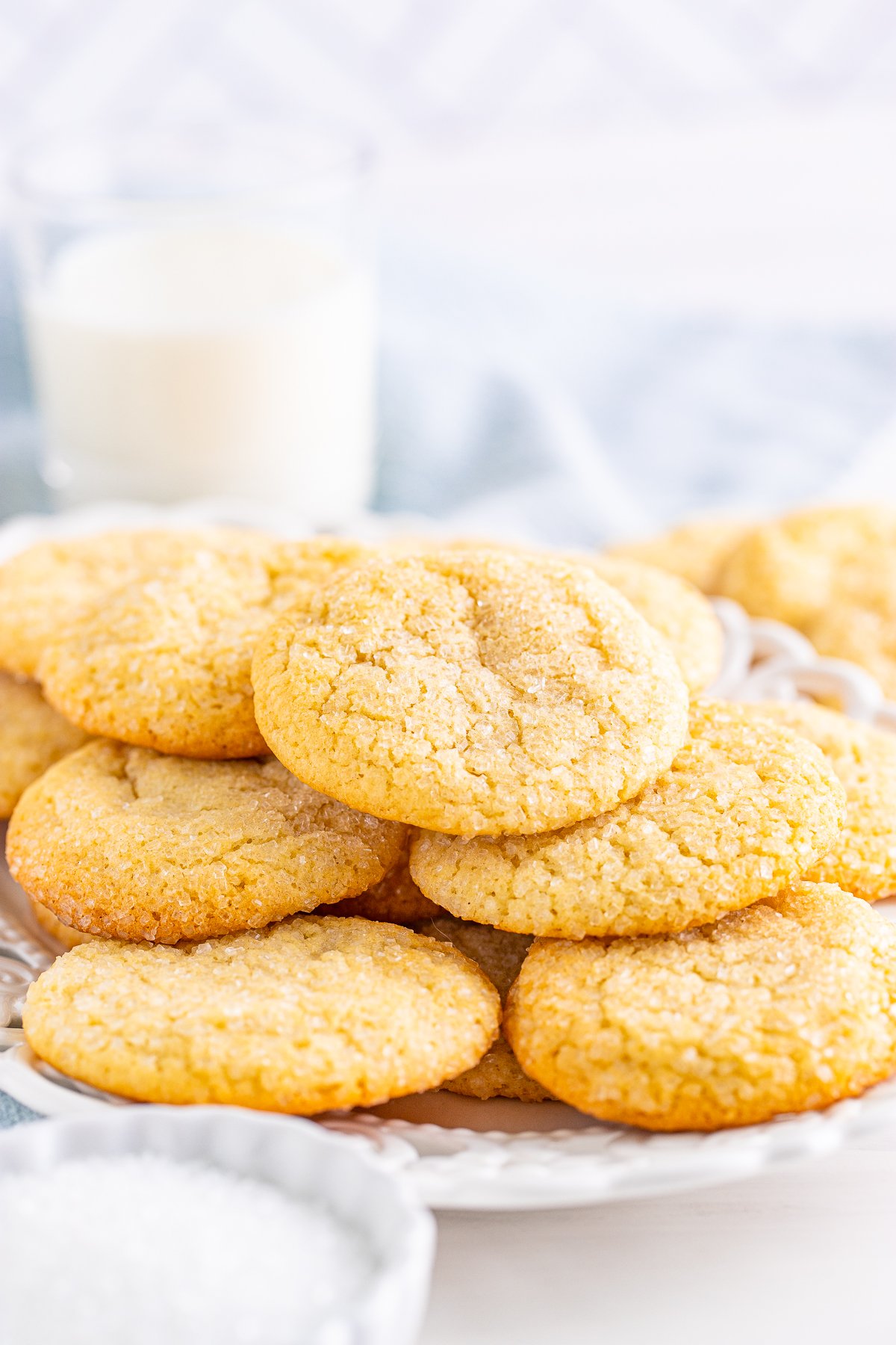 Chewy Sugar Cookies on white plate with milk in the background.