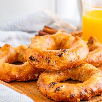 Layered Bagels on wooden board with orange juice in backgrounf.