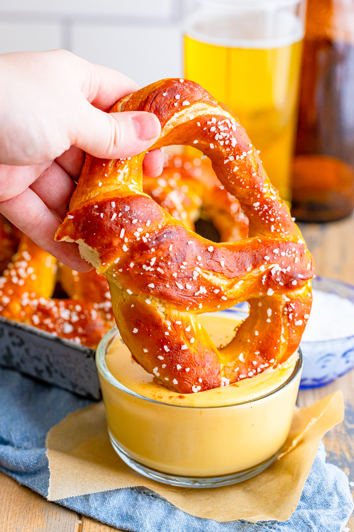 Hand dipping one Homemade Soft Pretzel into Beer Cheese Dip.