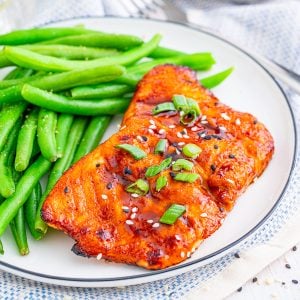 Square image of finished Salmon on plate with green beans.