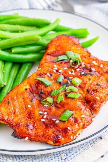 Square image of finished Salmon on plate with green beans.