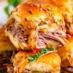 Close up of stacked French Dip Sliders showing melty provolone cheese and tender roast beef on Hawaiian rolls.