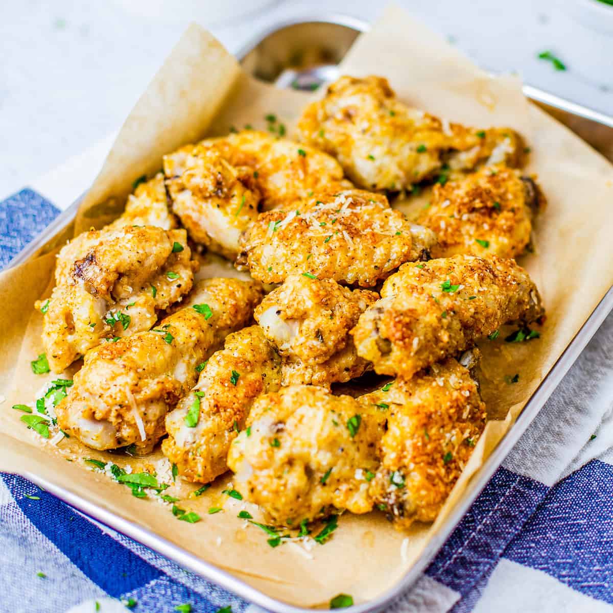 Crispy baked garlic parmesan wings piled in a serving dish with celery and dipping sauce.