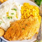 Square image of finished chicken on plate with corn and mashed potatoes.