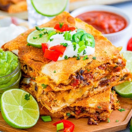 Square image overhead of cut and stacked Chicken Sheet Pan Quesadillas with toppings.