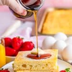 Syrup being poured over stack of cut Sheet Pan Pancakes on plate.