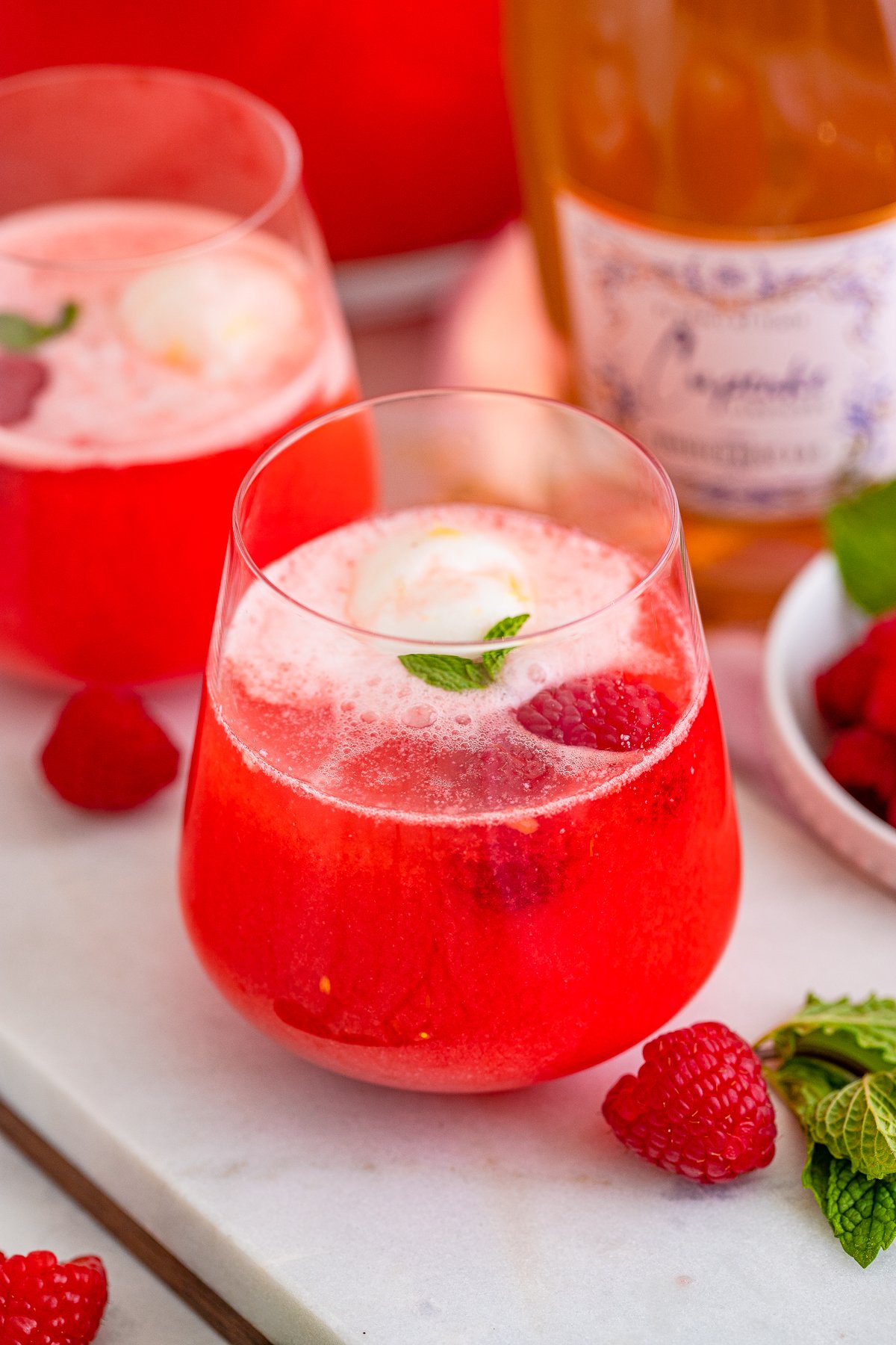 Two glasses of Valentine's Sherbet Punch with mint and raspberries around them.