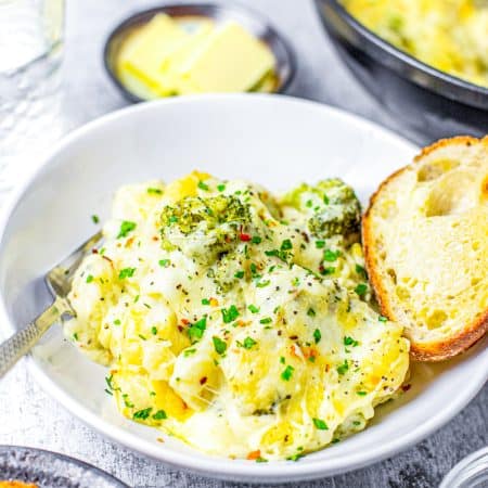 Bowl of cheesy broccoli gnocchi with toasted bread and a fork