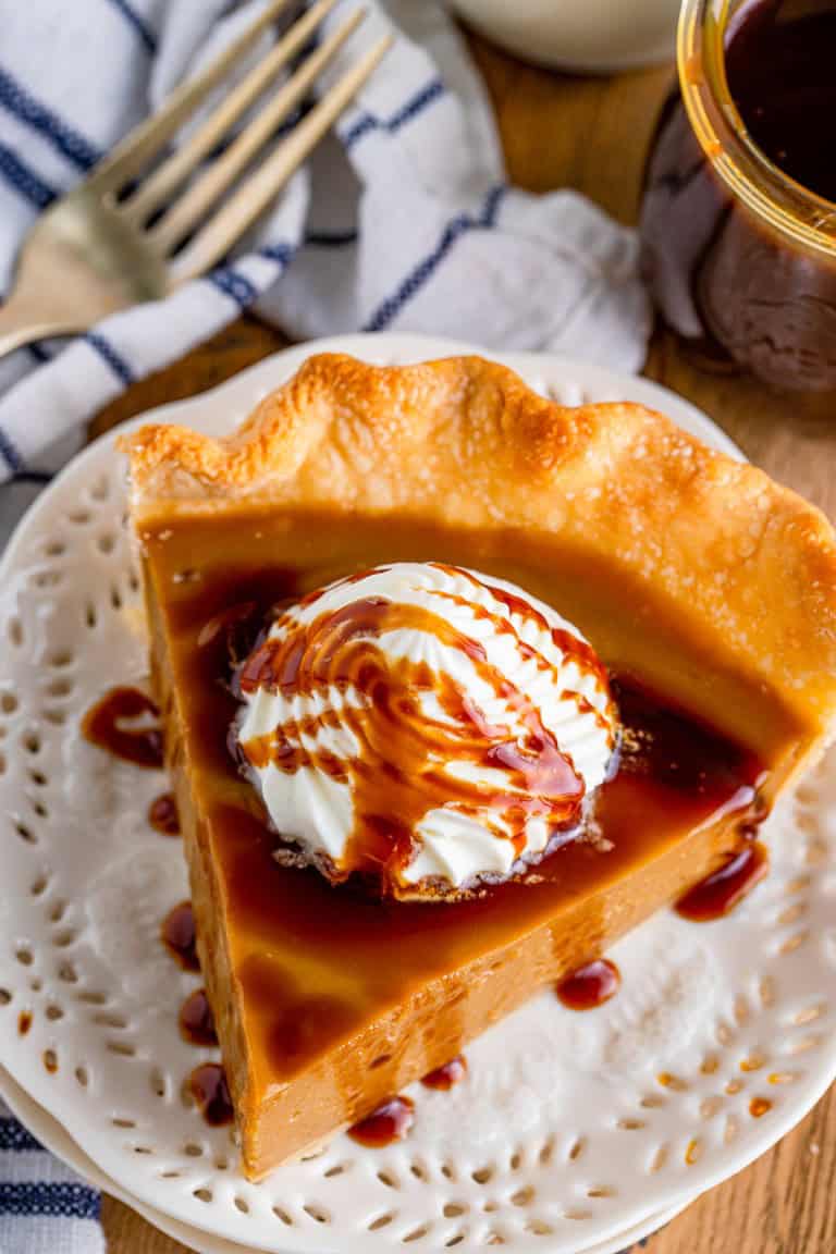 A slice of butterscotch pie topped with whipped cream and caramel drizzle.