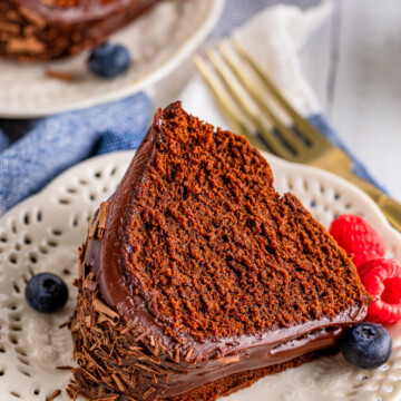 Slice of Chocolate Bundt Cake on white plate with berries.