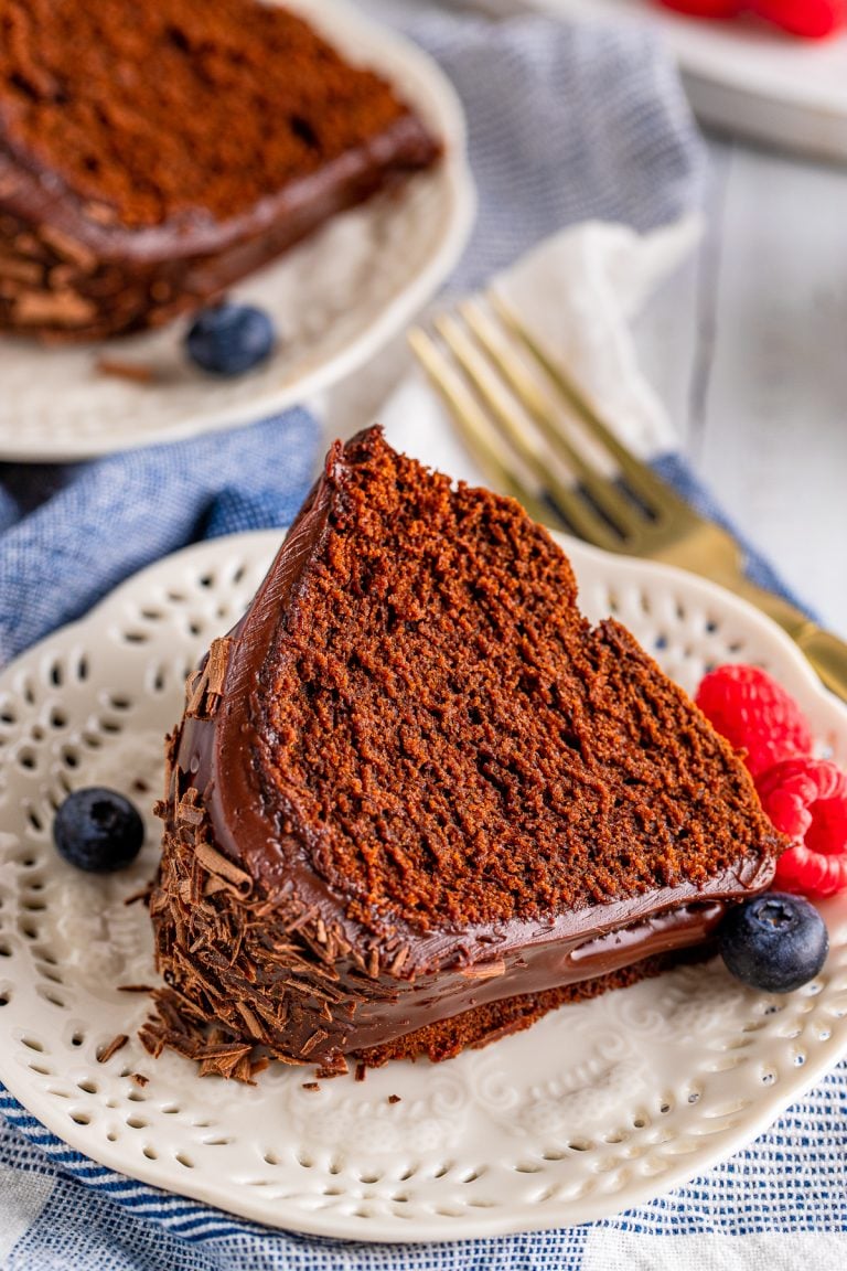Slice of Chocolate Bundt Cake on white plate with berries.