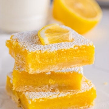 Lemon Bar Recipe Stacked three high topped with lemon quarter.