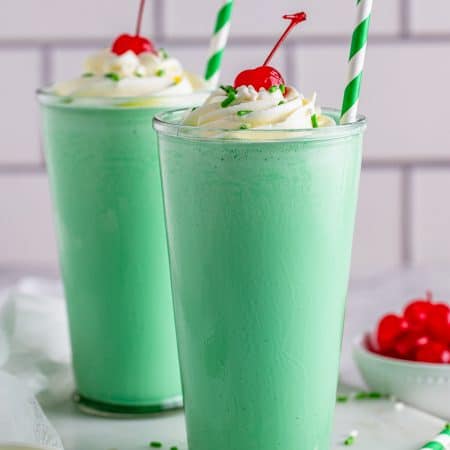 Two Shamrock Shake Recipes topped with whipped cream and a cherry.