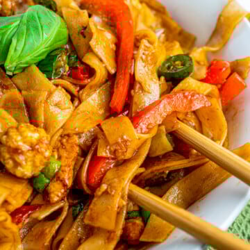Side view of Thai Drunken Noodles in bowl with chopsticks.