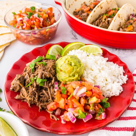 Slow Cooker Barbacoa Recipe on plate with pico, rice and guacamole.
