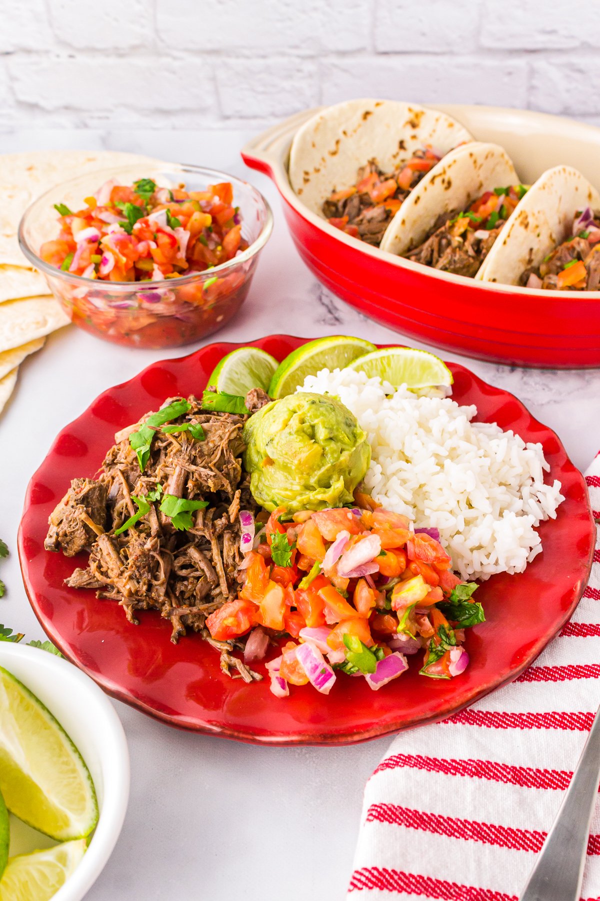 Slow Cooker Barbacoa Recipe on plate with pico, rice and guacamole.