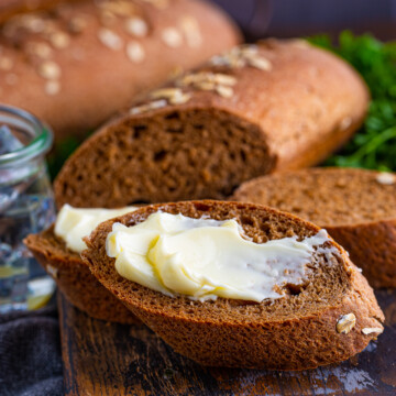 Slice of Cheesecake Factory Brown Bread spread with butter.