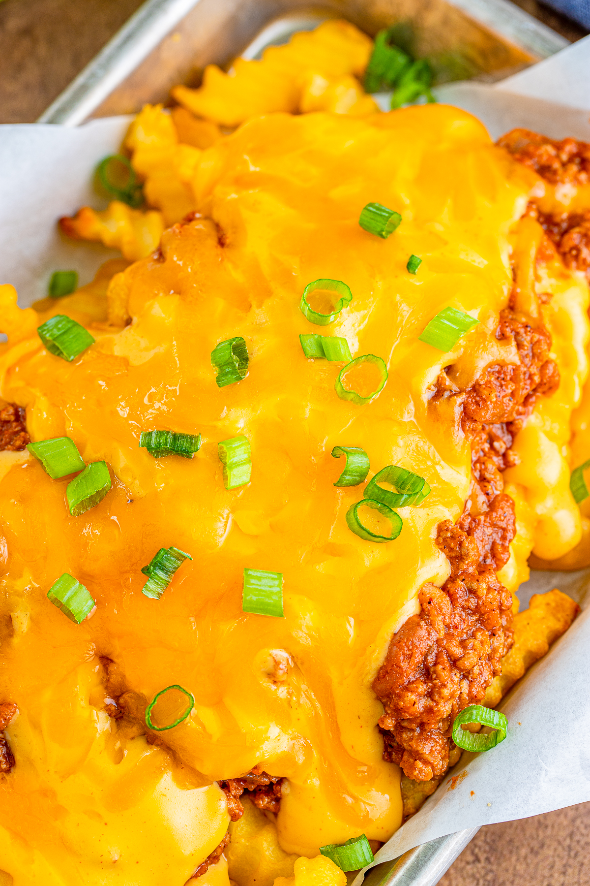 Overhead close up of melted cheese and green onions on Chili Cheese Fries.