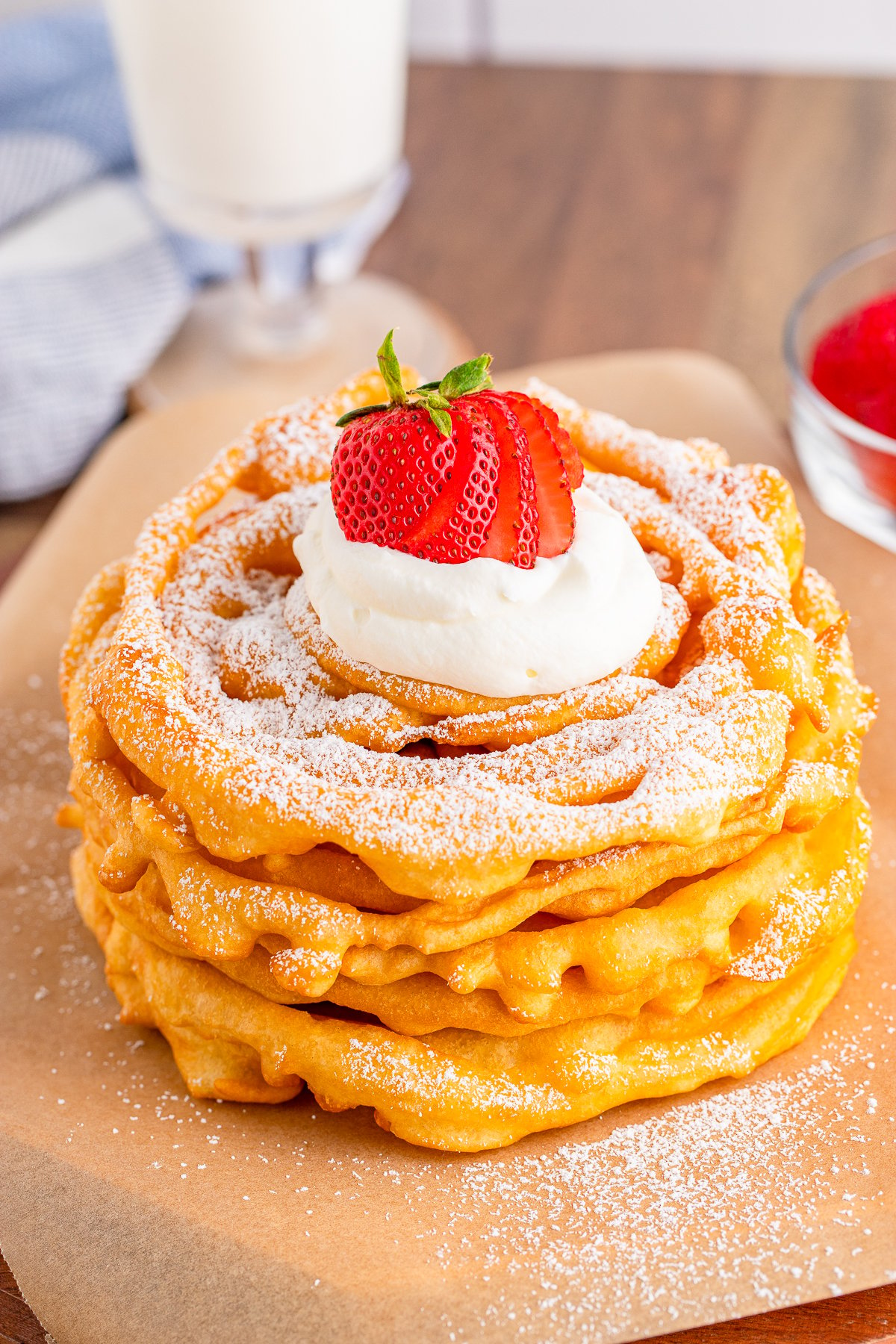 Slightly overhead view of stacked Funnel Cakes with garnishes.
