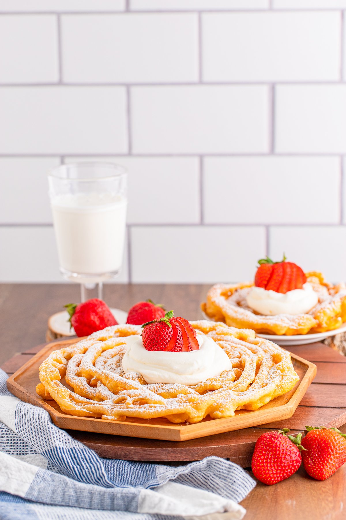 Two Funnel Cake Recipes on plates with garnishes.