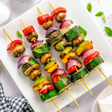 Overhead of kebabs on white platter.