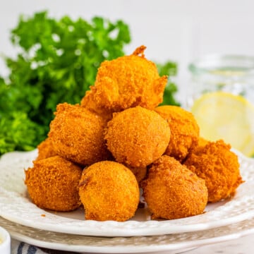 Stacked Hush Puppies on white plate.
