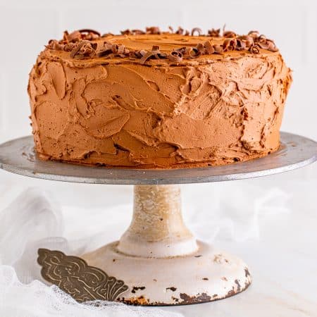 A whole frosted marble cake with chocolate frosting on a cake stand