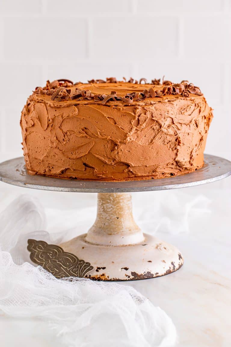 A whole frosted marble cake with chocolate frosting on a cake stand