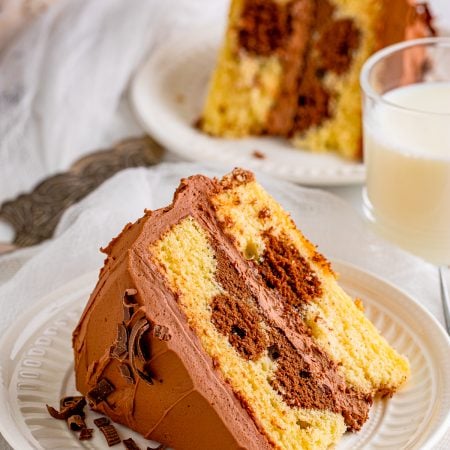 Slice of Marble Cake Recipe on white plate with milk and another slice in background.