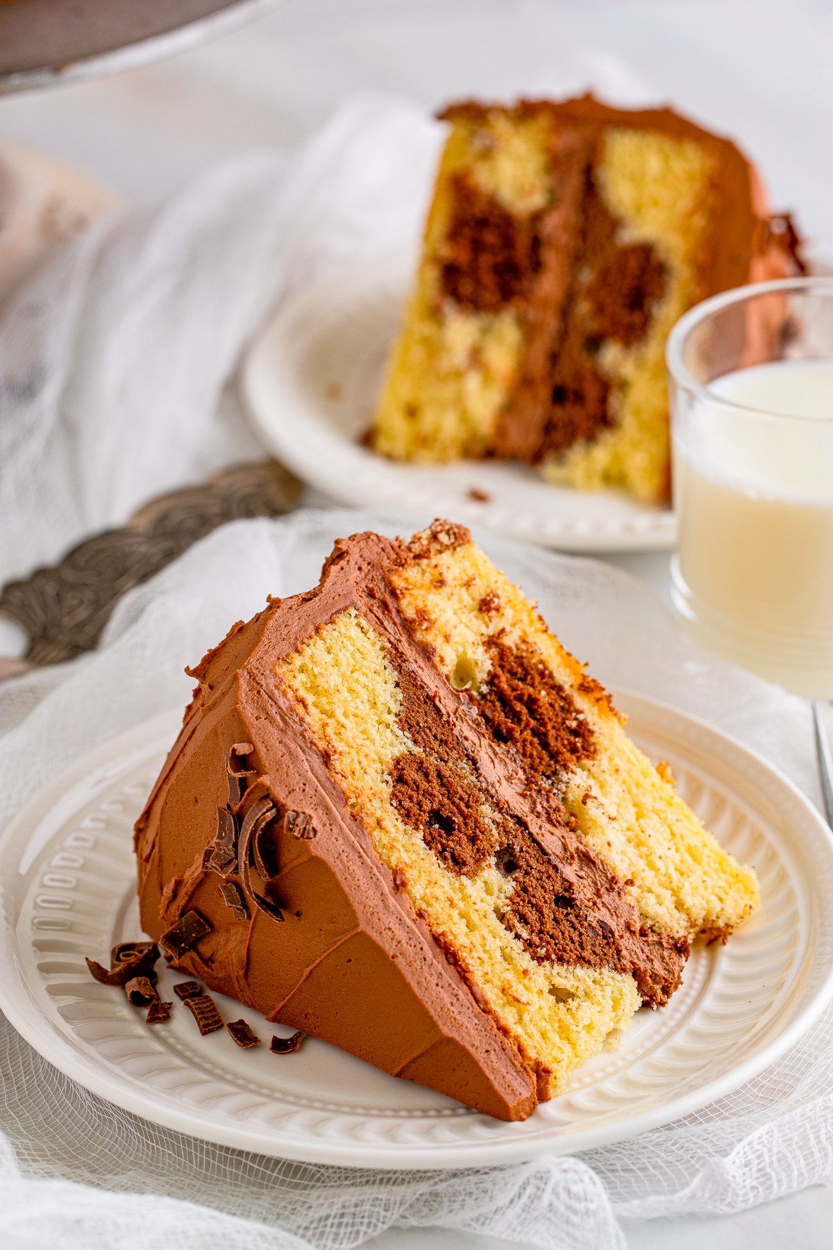 Slice of Marble Cake Recipe on white plate with milk and another slice in background.