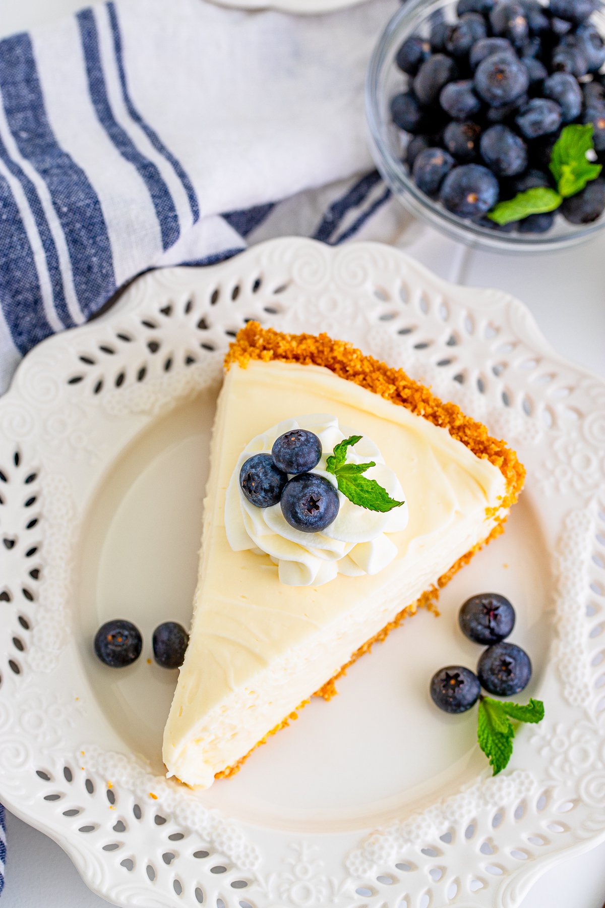 Overhead of slice of cheesecake on white plate with garnishes.